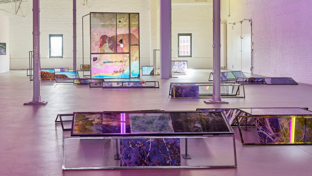 Euridice Zaituna Kala, Eutrophê: the wave (detail), 2025, iridescent metal frames, transfers on glass and metal, writing, engravings, seeds, glass. installation view Kunsthalle Münster 2026. Courtesy of the artist and galerie anne barrault. Photo: Moritz Hagedorn.