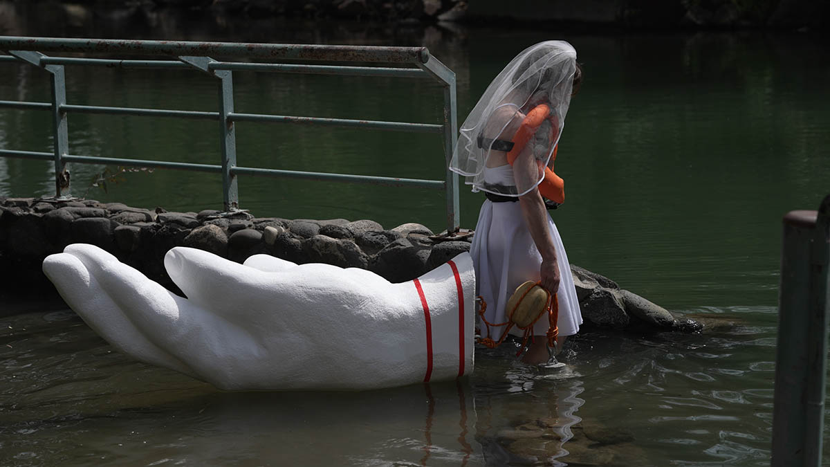 “My Savior, Yardenit”- video taken in the Jordan River, styrofoam hand, a personal life jacket, white dress, veil, wooden bead (Photo: Matan Meirson) 