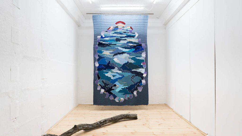 View of the exhibition 'Are we feeling blue_ An ode to the sea' in June 2021, Weaving (170cm x 250cm), tree brunch and video projection