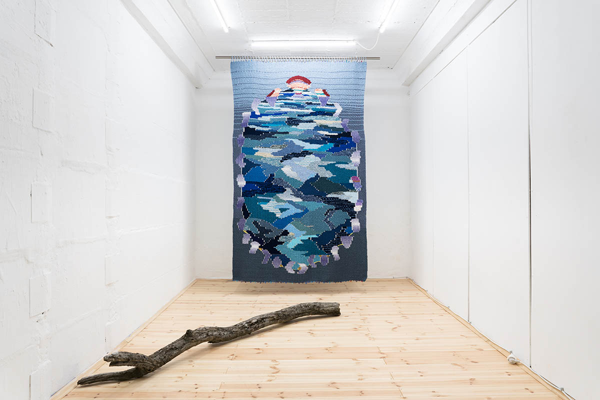 View of the exhibition 'Are we feeling blue_ An ode to the sea' in June 2021, Weaving (170cm x 250cm), tree brunch and video projection