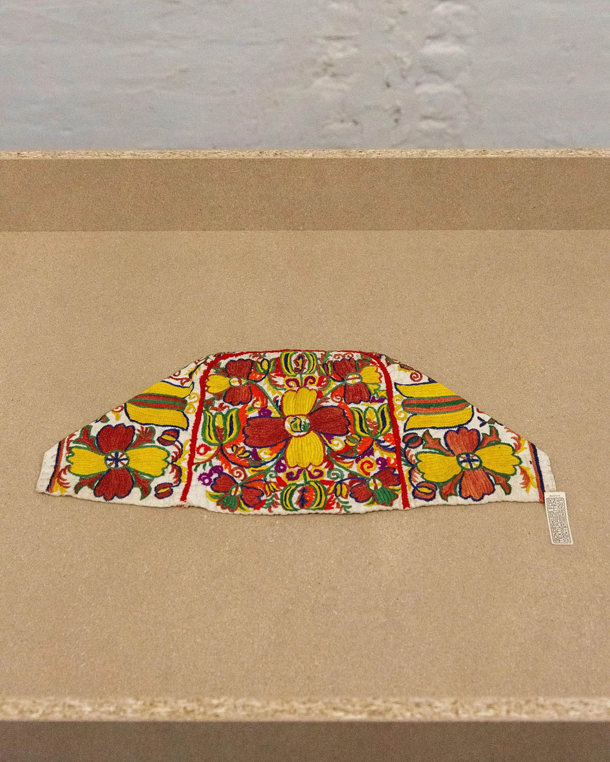 unknown artist, Schule / School Rosalia Rothansl, Bodenhaube, Lehrmittel / Bonnet, teaching material, 1909 - 1911, Cotton, embroidered, 18 × 41 × 0,5 cm, On loan from the Collection and Archive, University of Applied Arts Vienna. Photos: Aaron Amar Bhamra / Laurenz Courtesy of Laurenz 2026