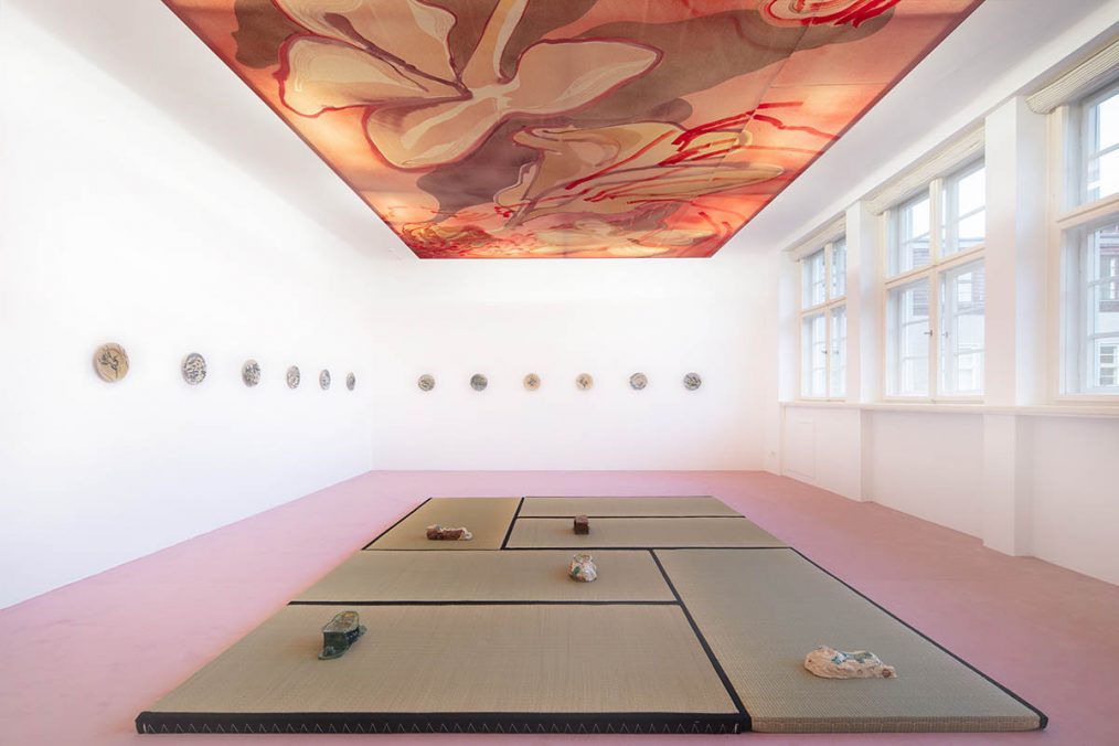 Installation view: Matthew Lutz-Kinoy. Window to The Clouds; Salon Berlin, Museum Frieder Burda Matthew Lutz-Kinoy, Wings of Flamingos, Camargue, 2020. Acrylic on canvas, 380 × 690 cm. Courtesy of the artist; Keramikos 3, 2019. Hand-painted set of 20 glazed ceramic plates. Courtesy of the artist and Mendes Wood DM São Paulo, New York and Brussels; Pillow In Cognac With Relaxed Figure, 2018; Pillow In The Form Of Reclining Child With Polkadots, 2018; Pillow In Green With Relaxing Figure, 2018; Pillow In The Form Of Reclining Child With Landscape, 2018; Pillow In The Form Of Reclining Child, Fishing Net, 2018. Glazed ceramics, dimensions variable. Courtesy of the artist and Fitzpatrick Gallery; Photo: Thomas Bruns